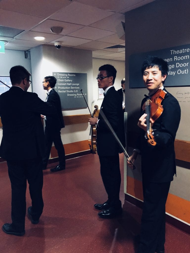 Willard Zhong (violin) prepares to go onstage with orchestra colleagues in Singapore. By Paul Dalgarno.