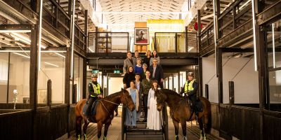 Victoria Police Mounted Branch members Monika Kusnierz (with Bob) and Christine Atherton (with Unity), flank Faculty of Fine Arts and Music students and staff, and architect Kerstin Thompson, in the refurbished Stables building. By Sav Schulman.