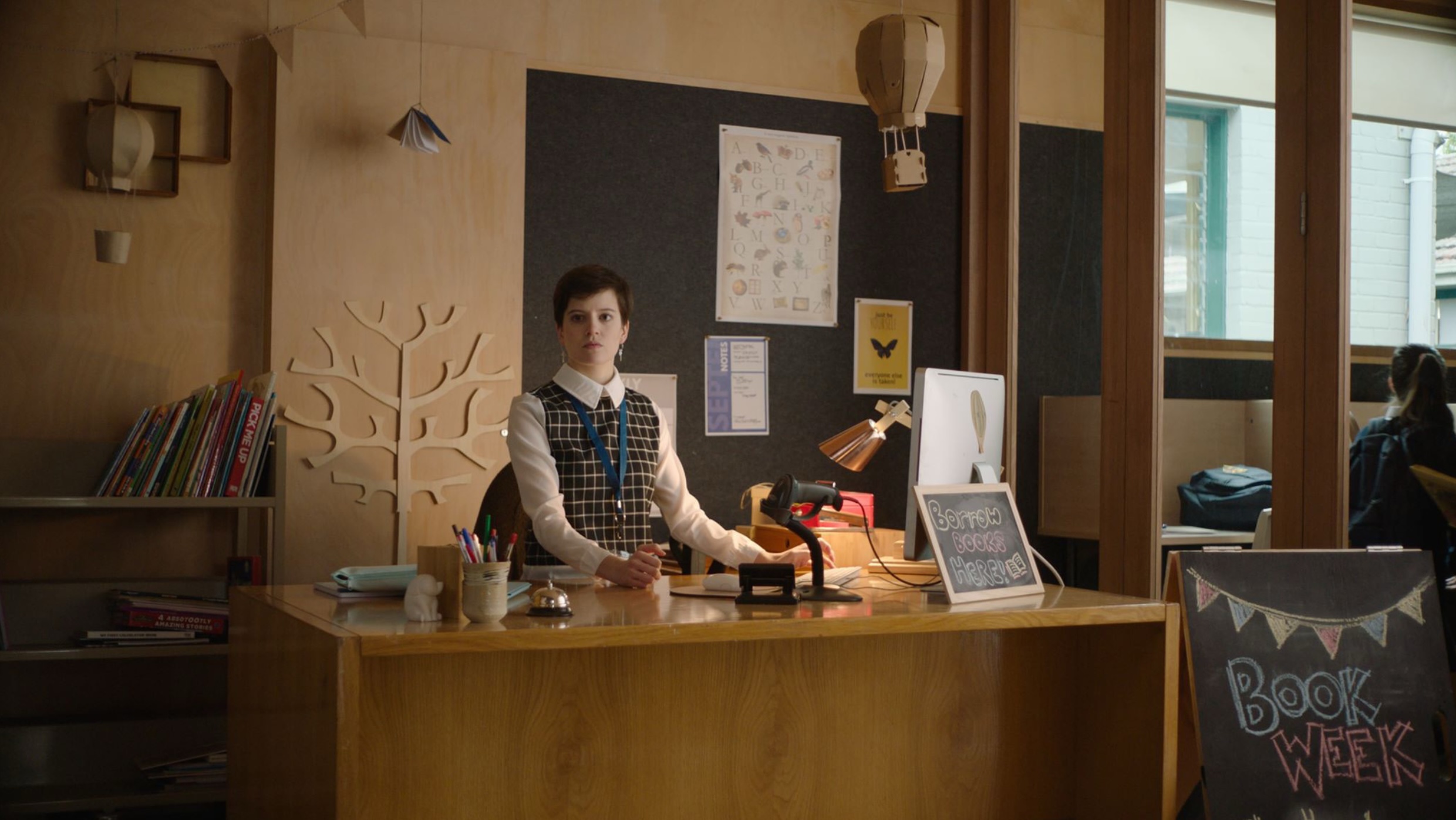 An actor sits at a desk in an office on a film set