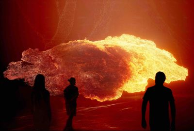 Three people stand in front of a giant screen with a large glowing ember on it