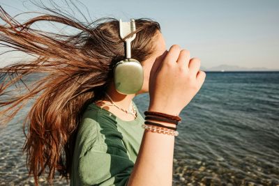 A young woman wearing headphones looks in the ocean