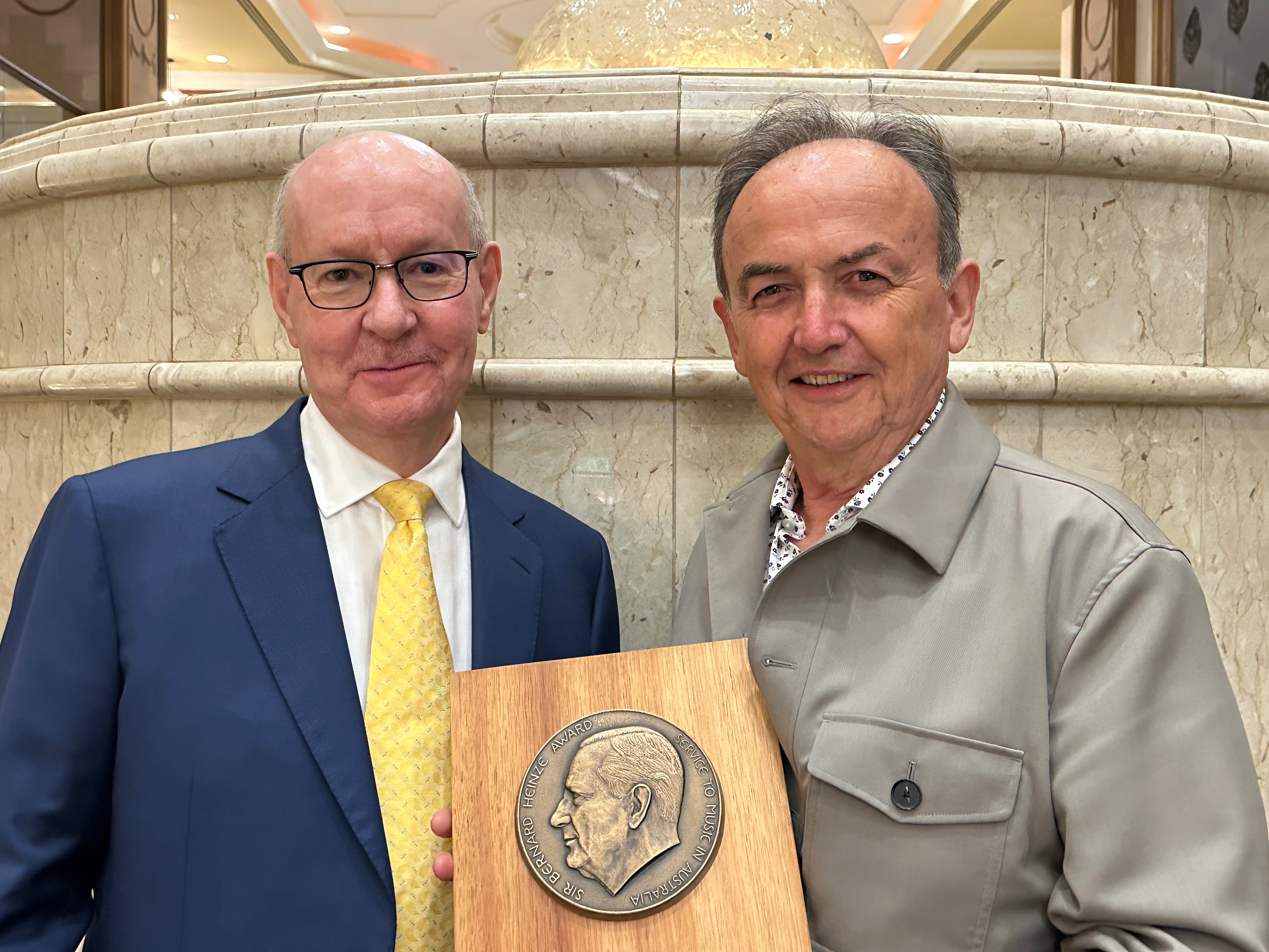 Two men stand holding an award.