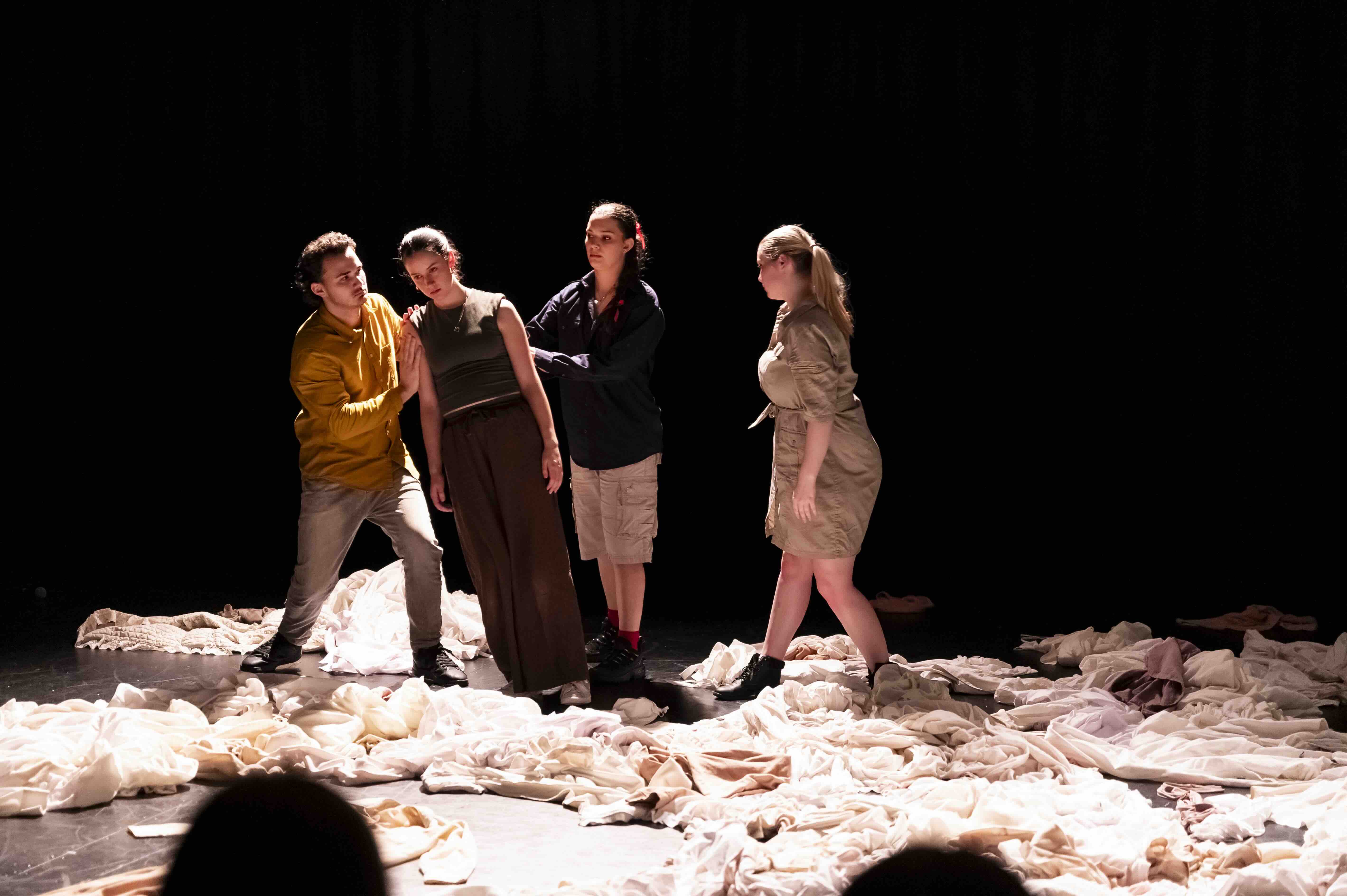 A group of four actors stand on a stage