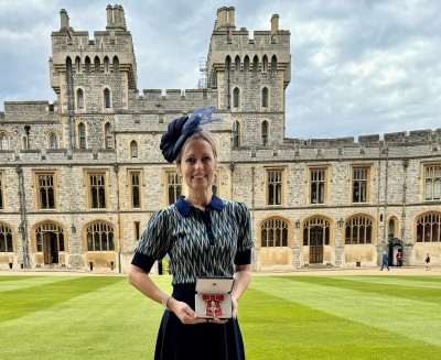 Professor Emma Redding holds award in front of Windsor Castle
