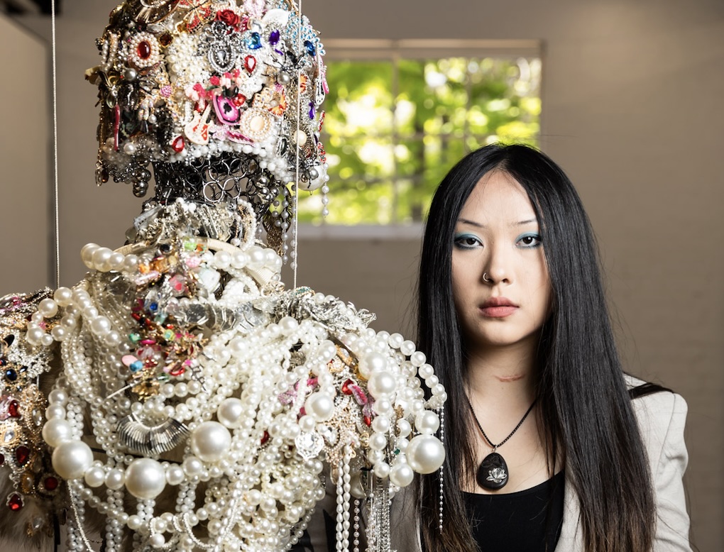 Artist standing next to heavily ornamented artwork