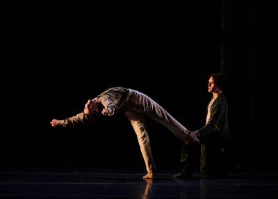 Two ballet dancers perform on a darkened stage