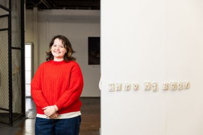 Artist stands next to an artwork that reads 'into my body'