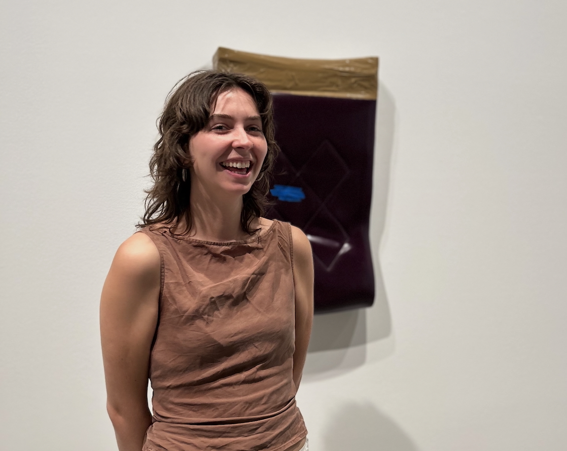 A woman stands in front of a painting smiling