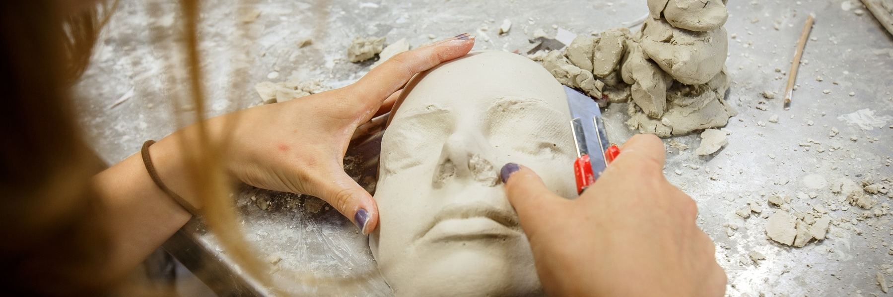 Student modelling a face out of clay material