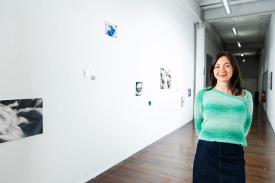 Artist stands in front of photos on wall
