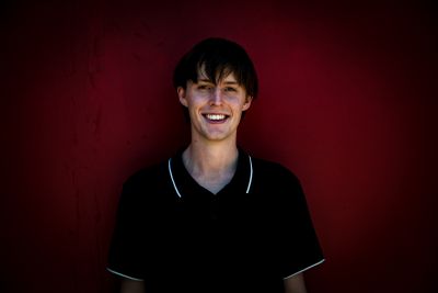 Photo of Thomas smiling in a black shirt against a red background