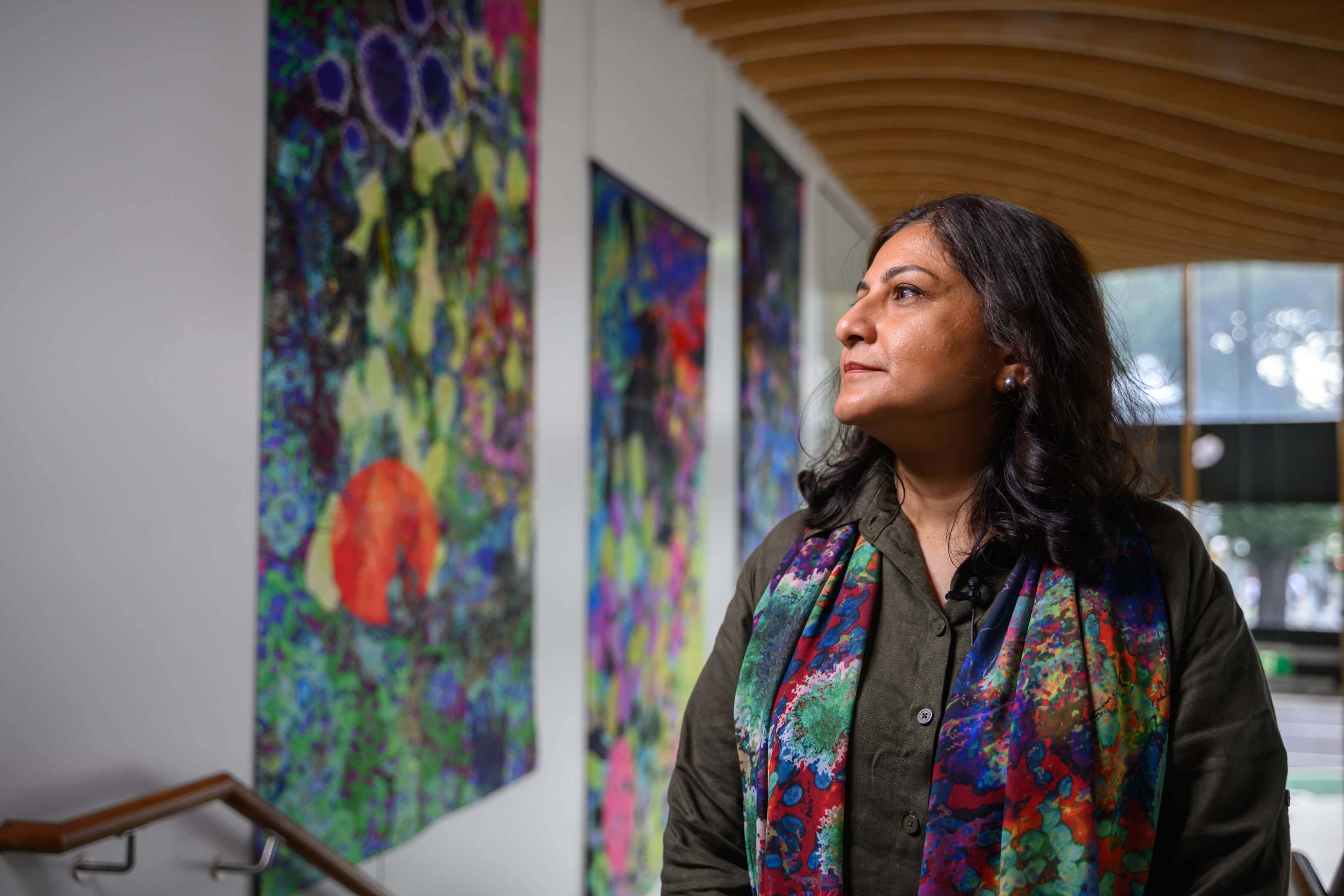 A woman stands looking at colourful artworks