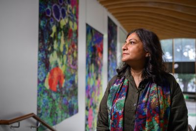 A woman stands looking at colourful artworks