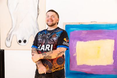 Artist standing in front of two paintings