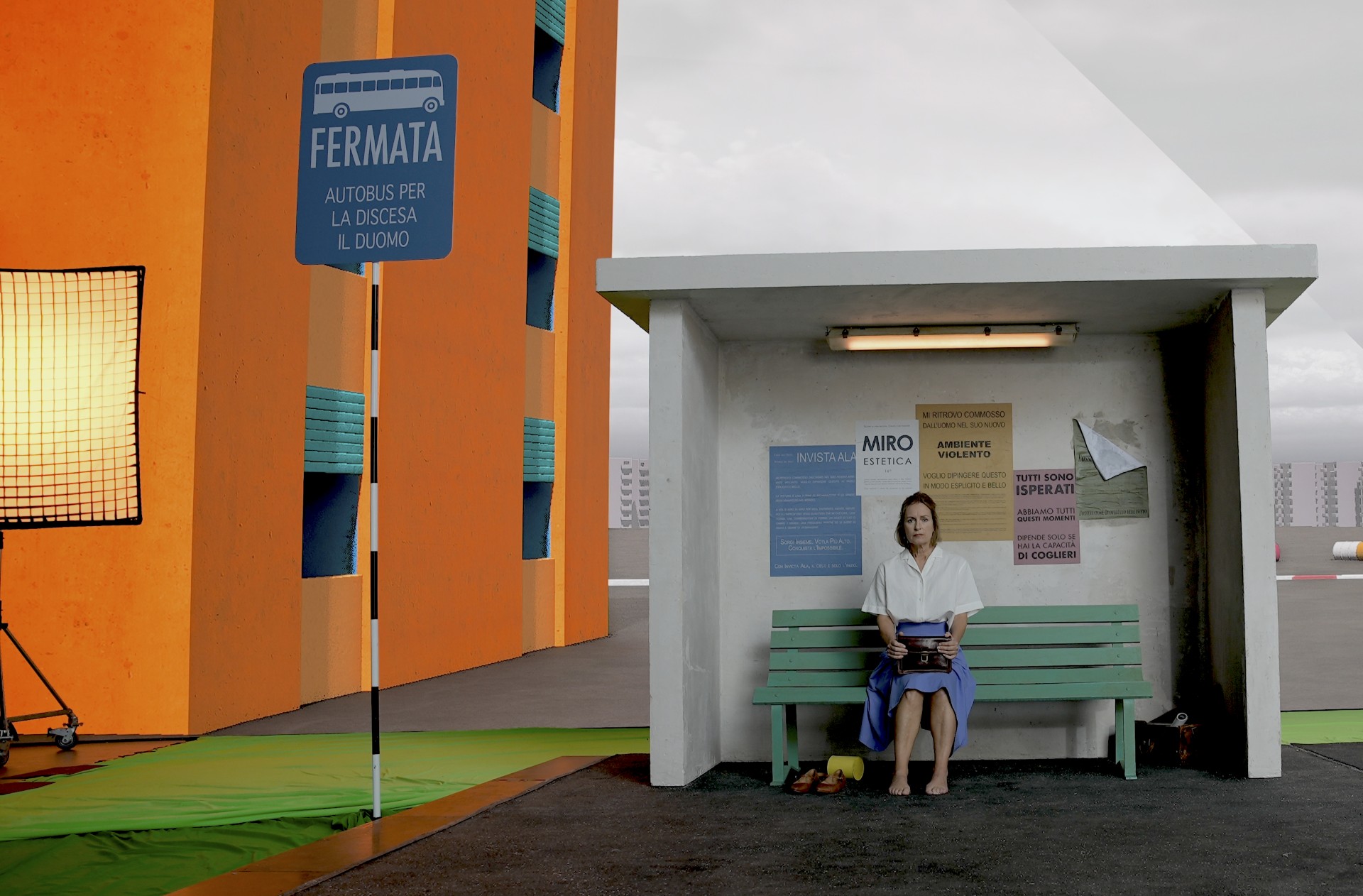 A women sits at a bus stop on a film set
