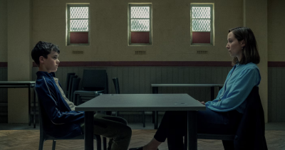 A teenage boy and a woman look at each other across a table