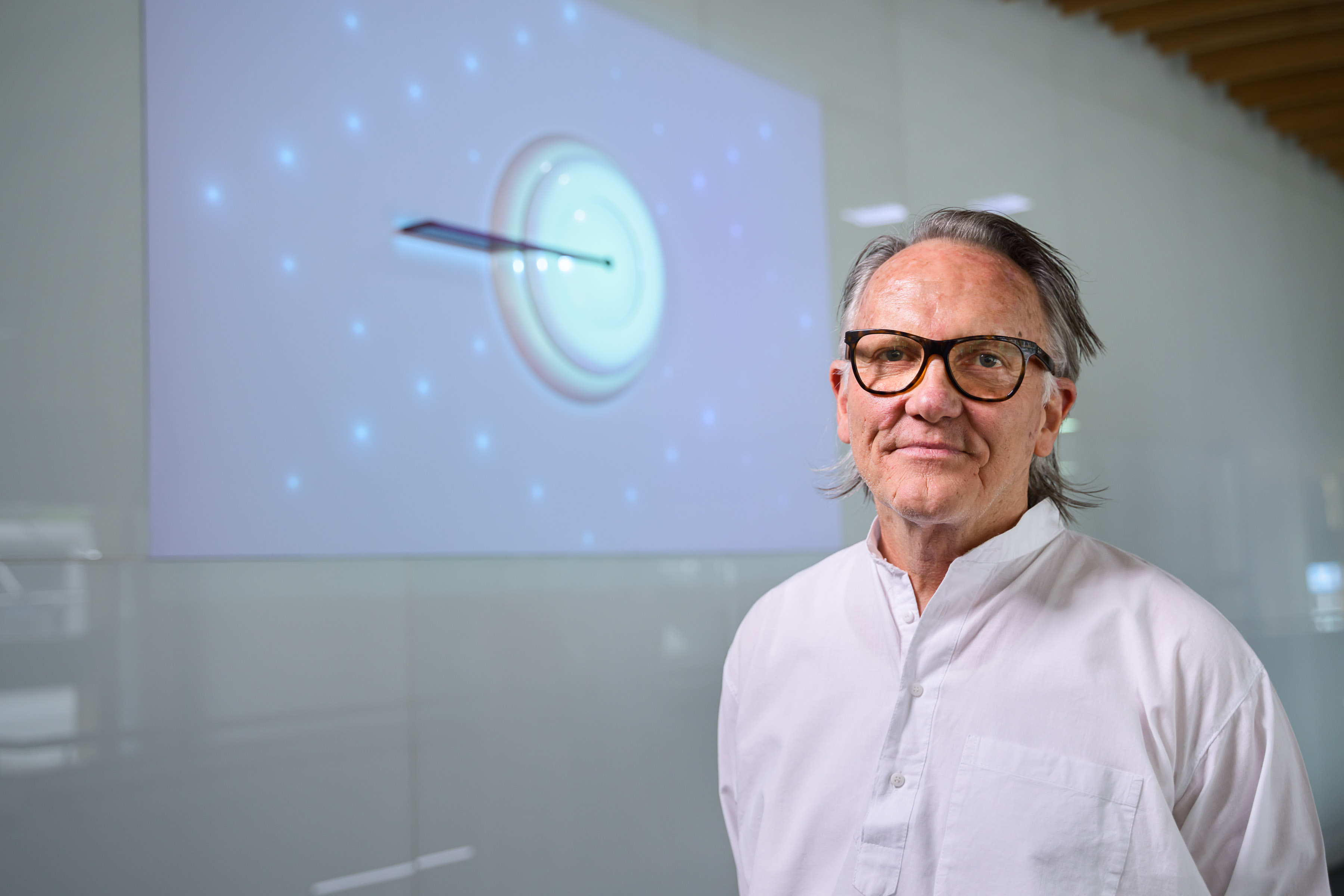 Artist John Meade. Image credit: Peter Casamento. A man stands in front of an abstract artwork