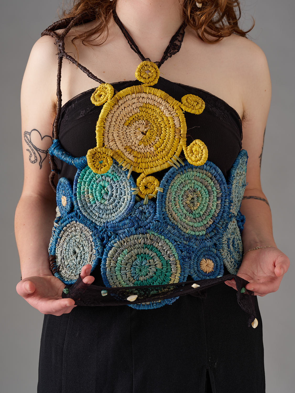 A person wears a woven raffia garment