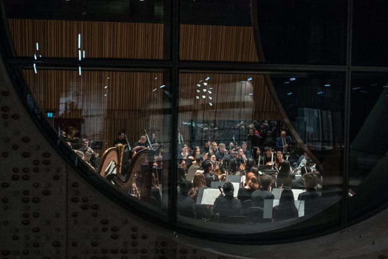 The University of Melbourne Symphony Orchestra viewed through the giant ‘oculus’ window at The Ian Potter Southbank Centre on 1 June, 2019. By Stephen McCallum.