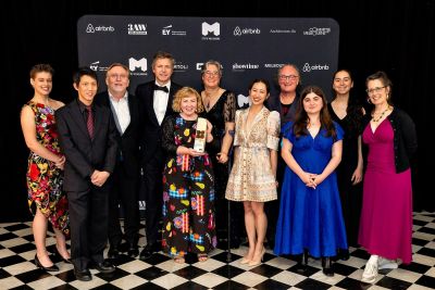 Eleven people stand with an award at an awards ceremony