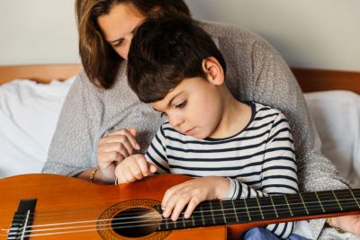 A child plays guitar with an adult